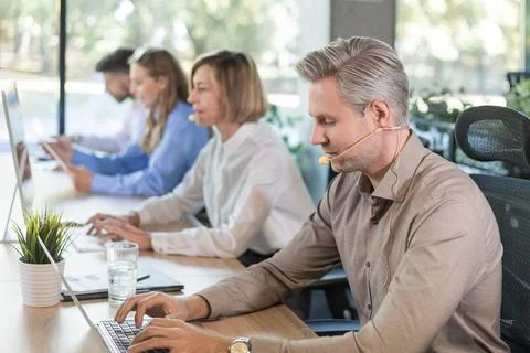 Portrait of call center worker accompanied by his team. Smiling customer supp Foto stock