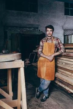 Portrait of carpenter standing by timber stack in workshop Stock Photos