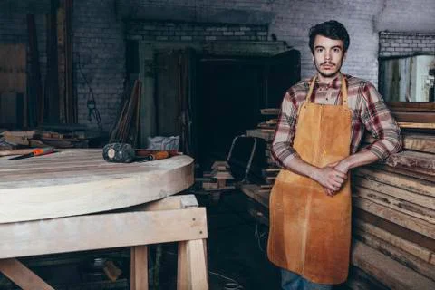 Portrait of carpenter standing by timber stack in workshop Stock Photos