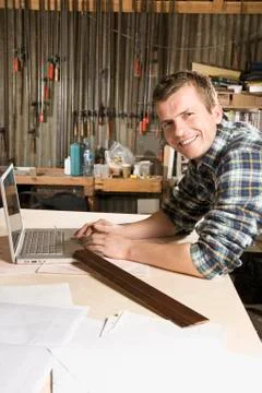 Portrait of a carpenter using a laptop in a workshop Stock Photos