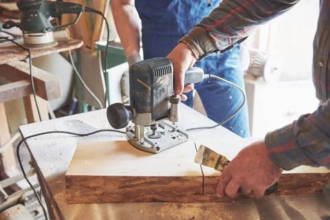 Portrait of a carpenter in working clothes in the workshop of the joiner's .. Stock Photos
