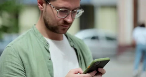 Portrait of casual man in glasses using smartphone on the street. Handsom Stock Footage 197617872