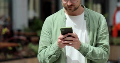 Portrait of casual man using smartphone outdoor. Cheerful man typing messages on Stock Footage 197616719