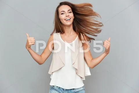 Portrait of a casual smiling young woman showing thumbs up Stock Photos