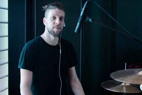 Portrait of a caucasian bearded drummer on a black stage behind a drum kit Stock Photos