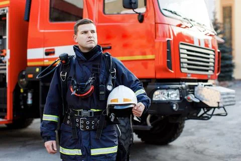 Portrait of caucasian Firefighter in uniform and helmet near fire engine. Stock Photos