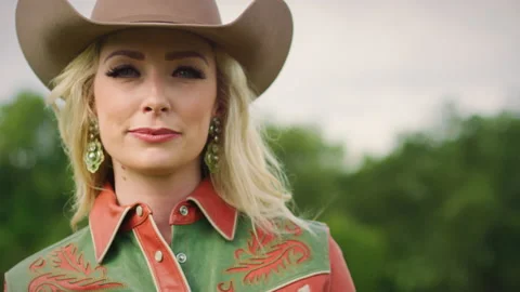Portrait of a Caucasian girl wearing a cowboy hat, standing on her farm, looking Stock Footage