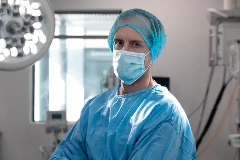 Portrait of caucasian male doctor standing in operating theatre wearing face Stock Photos