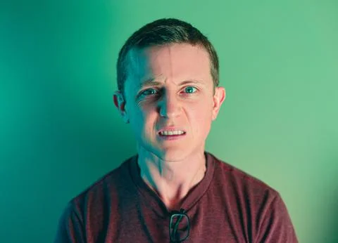 A portrait of a Caucasian man with a grumpy expression on his face against gr 스톡 사진