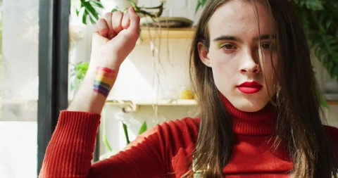 Portrait of caucasian non-binary transgender woman raising hand with lgbt flag 動画素材 343511923