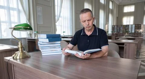 Portrait of caucasian Senior man working with book in public library. Stock Photos