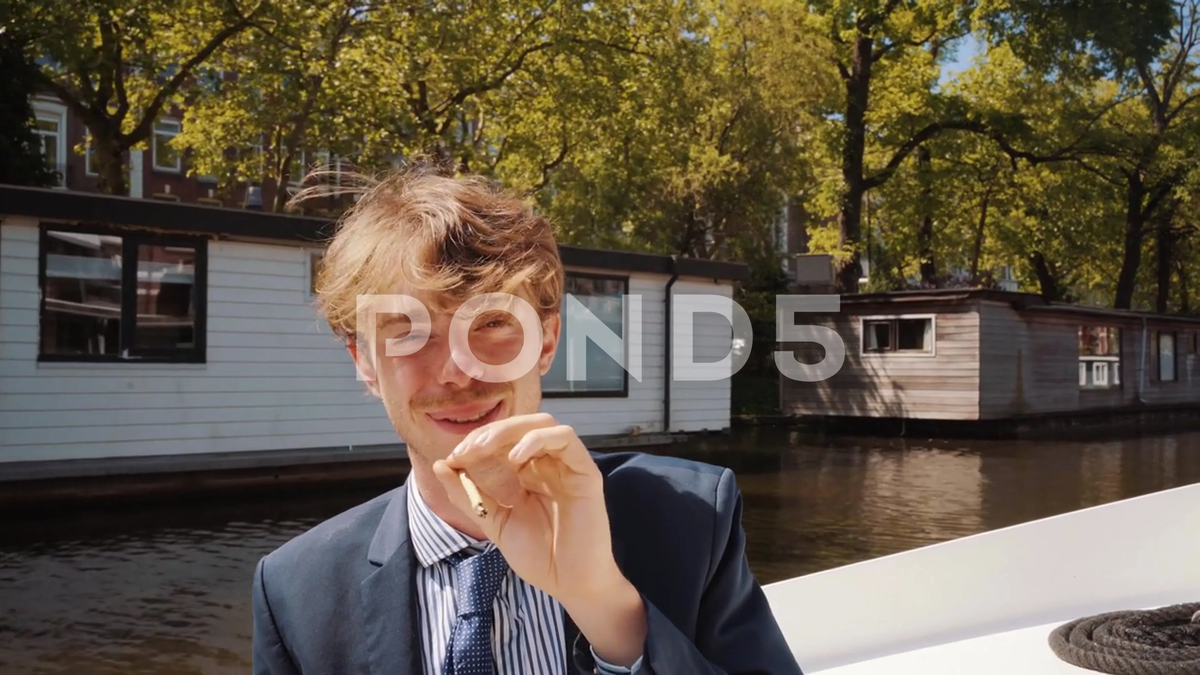 Portrait of caucasian young adult on Amsterdam boat canal smoking joint of