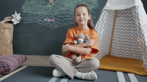 Portrait of charming child hugging stuffed toy smiling looking at camera at home Video stock 163266530
