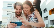 Portrait Of The Charming Happy Loving Couple Using Mobile Phone While Sitting On Stock Footage
