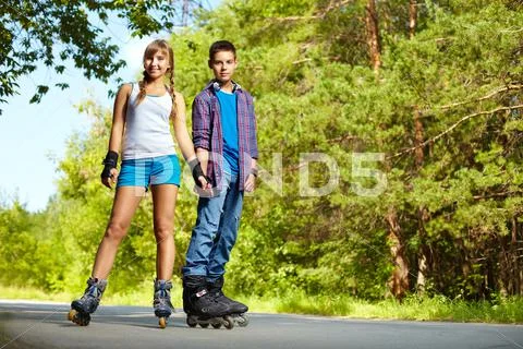 Portrait of a charming teenage couple roller-skating together Stock Photos