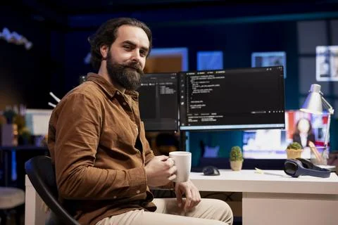 Portrait of cheerful computer engineer drinking coffee and debugging code Foto stock