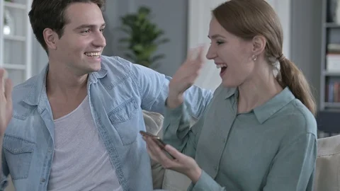 Portrait of Cheerful Couple Celebrating While Using Smartphone Video stock 118668683