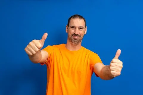 Portrait of cheerful man in basic clothing smiling and showing thumbs up at.. Stock Photos