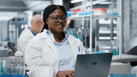 Portrait of cheerful scientist using laptop software in laboratory Stock Photos