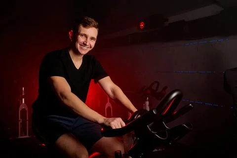 Portrait of cheerful sportsman on stationary maching bike in health club Stock Photos
