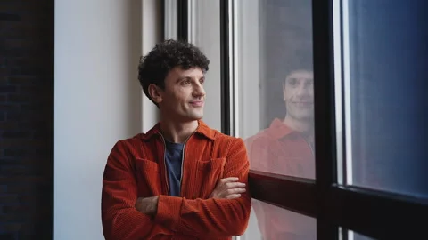 Portrait of cheerful young man with folded arms looking out the window, optimism Stock Footage 337908393