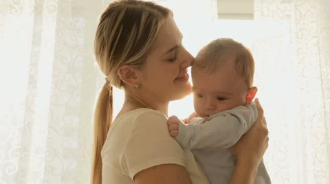 Portrait of cheerful young mother with her baby boy in sun rays in front of b Stock Footage