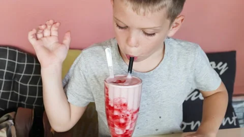 Portrait of child drinking strawberry shake. Video stock 274253308