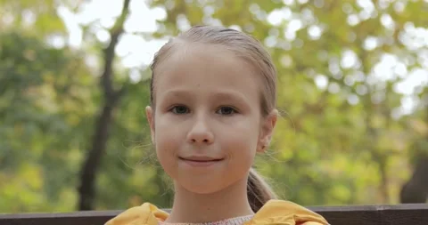 Portrait of a child looking at the camera. Cute baby is sitting on a park bench. Stock Footage 163315560
