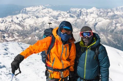Portrait climber in a down jacket and harness he is standing next to his friend Stock Photos