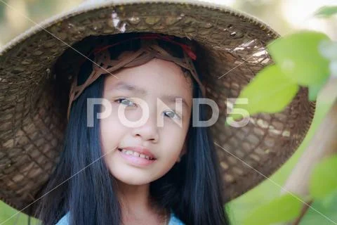 Portrait close up shot Asian little girl wearing farmer hat in green nature f Stock Photos