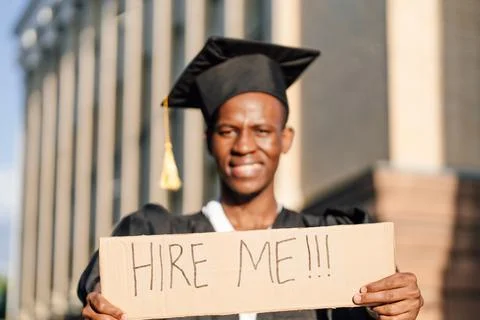 Portrait closeup of black guy standing with cardboard poster on street in sunny Stock Photos