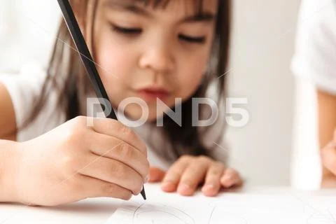 Portrait closeup of brunette girl 7y in defocus drawing painting, on white pa Stock Photos