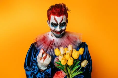 A portrait of a clown  with a bouquet of flowers. Halloween, carnival, actor. Stock Photos