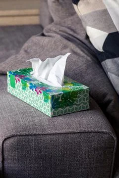 A portrait of a colorful box of paper tissues standing on the side of a couch Stock Photos