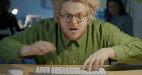 Portrait of comic guy working with computer typing in rush looking at camera Stock-Footage 217333085