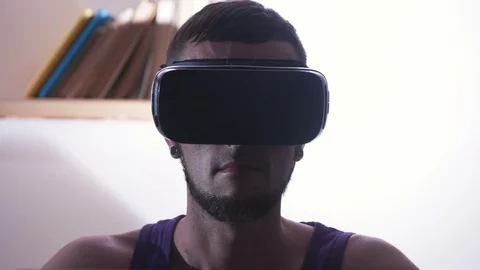 Portrait of concentrated guy in VR headset sitting at table in living room. VR Stock Footage 98190942