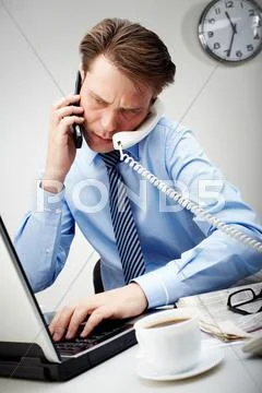 Portrait of confident businessman calling by two phones and typing simultaneousl Stock Photos