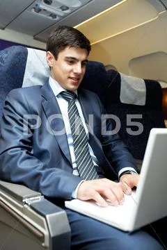 Portrait of confident businessman typing on laptop during flight Stock Photos