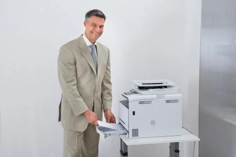 Portrait of confident businessman using printer in office Stock Photos