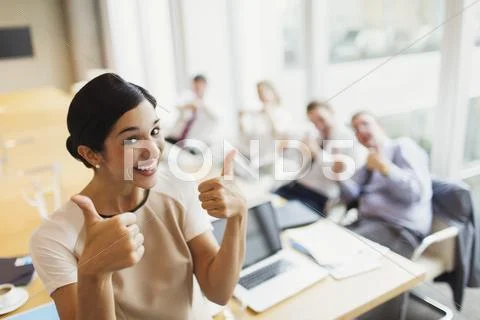Portrait confident businesswoman and colleagues gesturing thumbs-up in Stock Photos