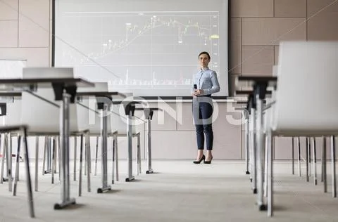 Portrait confident businesswoman with microphone at projection screen with chart Stock Photos