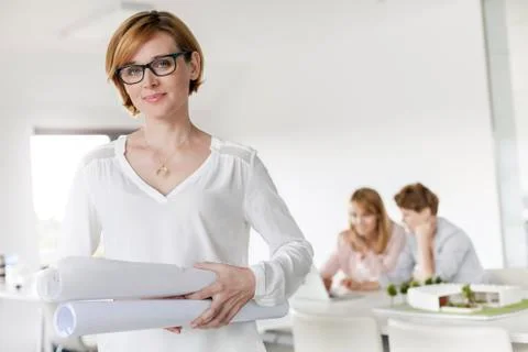 Portrait confident female architect holding blueprints in conference room Stock Photos