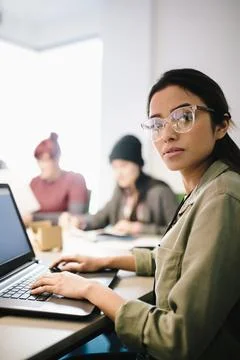 Portrait confident female computer programmer coding at laptop in office Foto stock