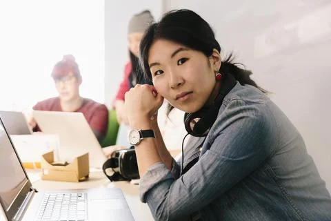Portrait confident female computer programmer coding at laptop in office Stock Photos