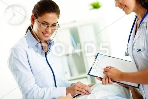 Portrait of confident female doctors during medical treatment of patient in hosp Stock Photos