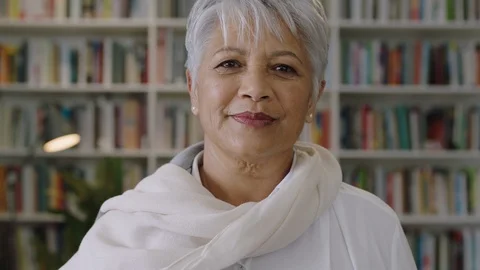 Portrait of confident friendly indian middle aged  teacher standing in library Stock Footage