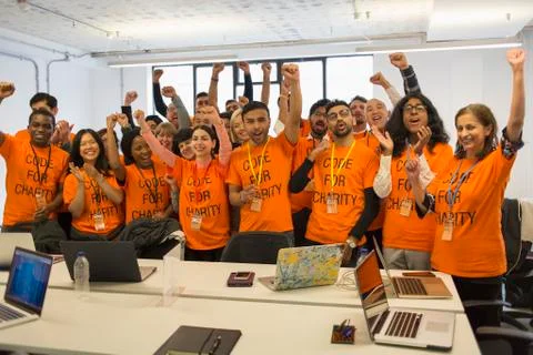 Portrait confident hackers cheering, coding for charity at hackathon Foto stock