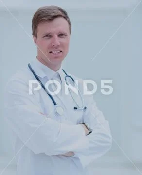Portrait of confident male doctor with arms crossed standing at Stock Photos