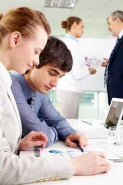 Portrait of confident man looking at document with female near by in working env Stock Photos