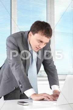 Portrait of confident man at workplace typing on laptop Stock Photos